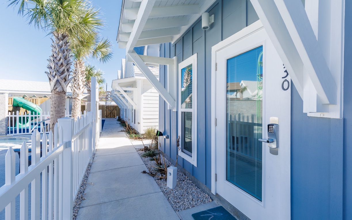Charming coastal property features bright blue exteriors with white trim, welcoming entrance, and tropical palm landscaping in a beach community setting.