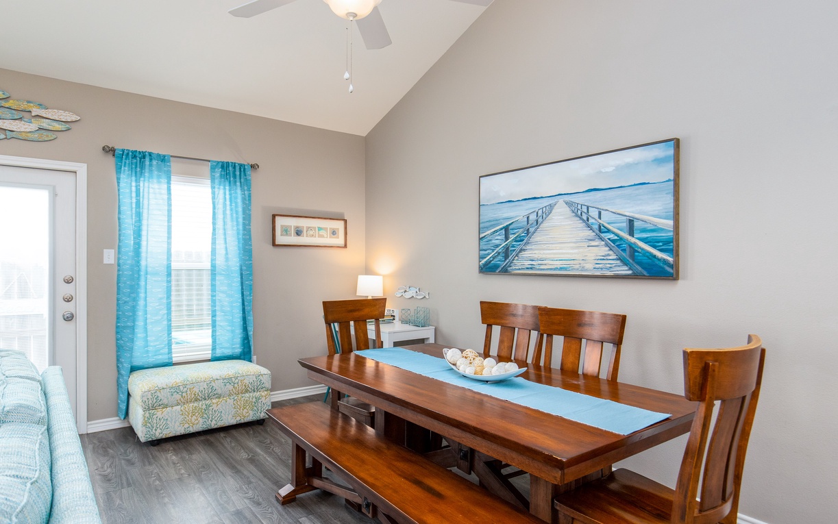 Gather around your elegant dining table for memorable meals, with warm wood tones and coastal artwork creating the perfect atmosphere.