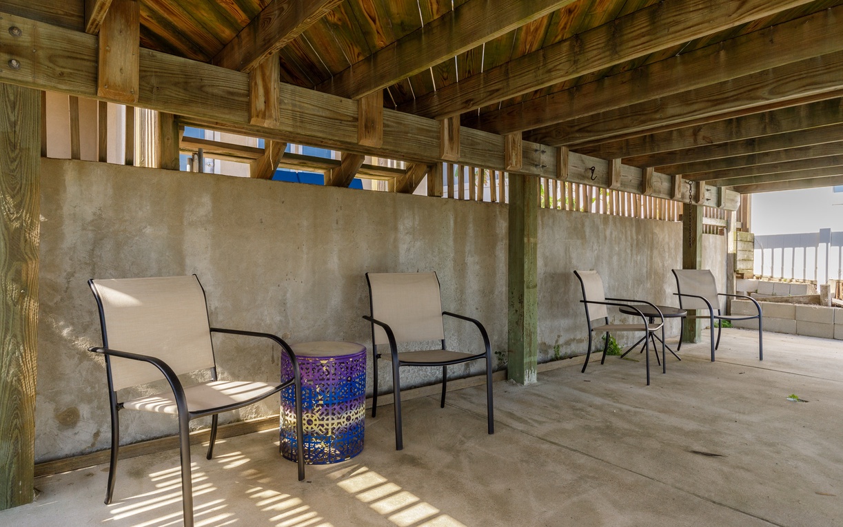 Unwind in your private covered patio where comfortable seating awaits beneath rustic wooden beams, creating the perfect shaded retreat.