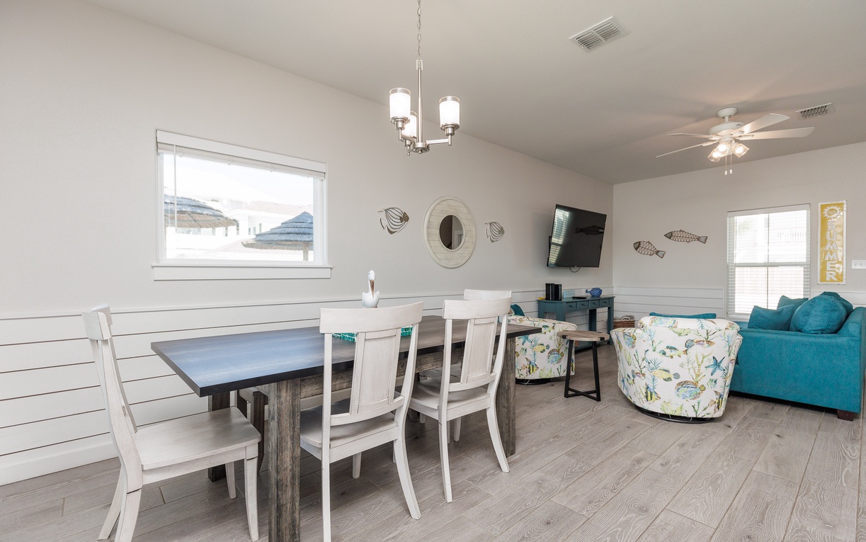 Relax in this bright, coastal-themed living space where you can gather around the dining table or unwind on comfy seating.