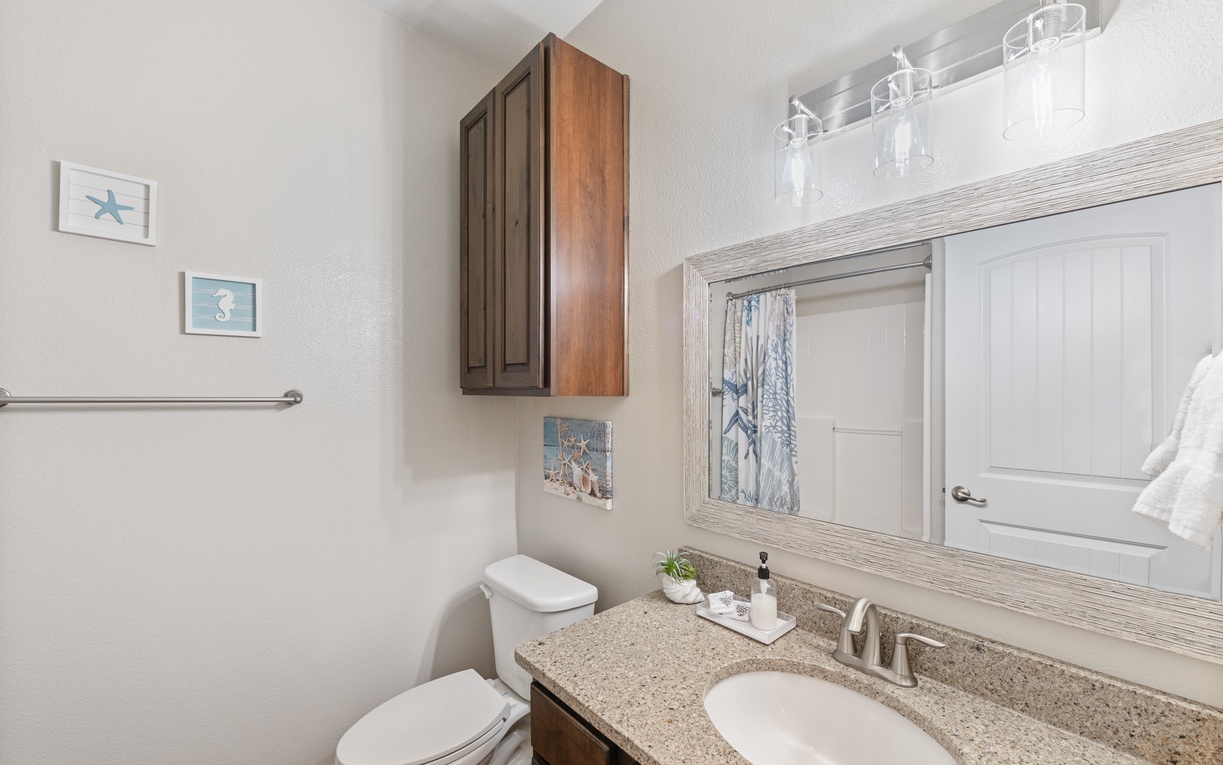 Your private bathroom features granite countertops, coastal artwork, and modern vanity lighting to create your perfect morning routine sanctuary.