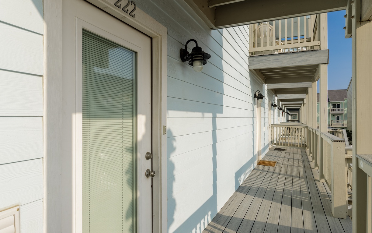 Charming covered walkway leads to your beachside retreat, where coastal architecture and peaceful balconies create the perfect seaside escape.