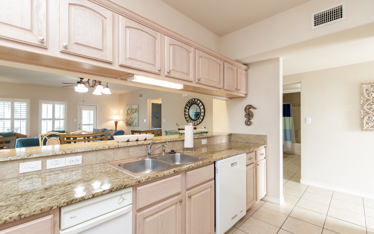 Your spacious kitchen features granite countertops, white appliances, and elegant cabinetry perfect for preparing vacation meals.