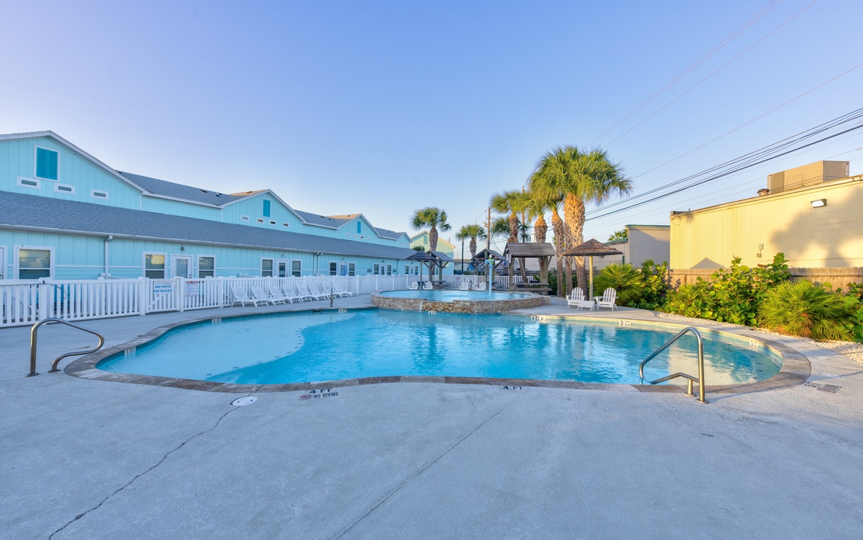A sparkling blue pool surrounded by tropical palms creates the perfect backdrop for your beach vacation getaway.