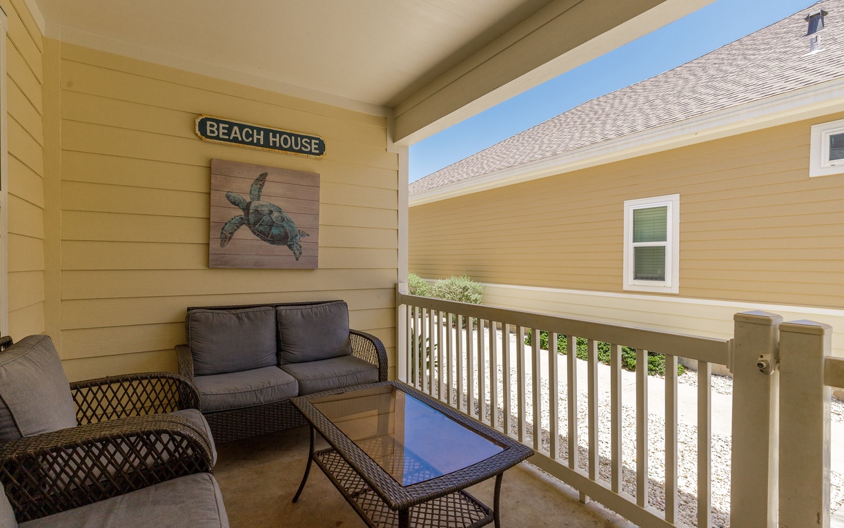 Relax on your private covered balcony with comfortable seating and charming beach house décor, perfect for morning coffee or evening unwind.