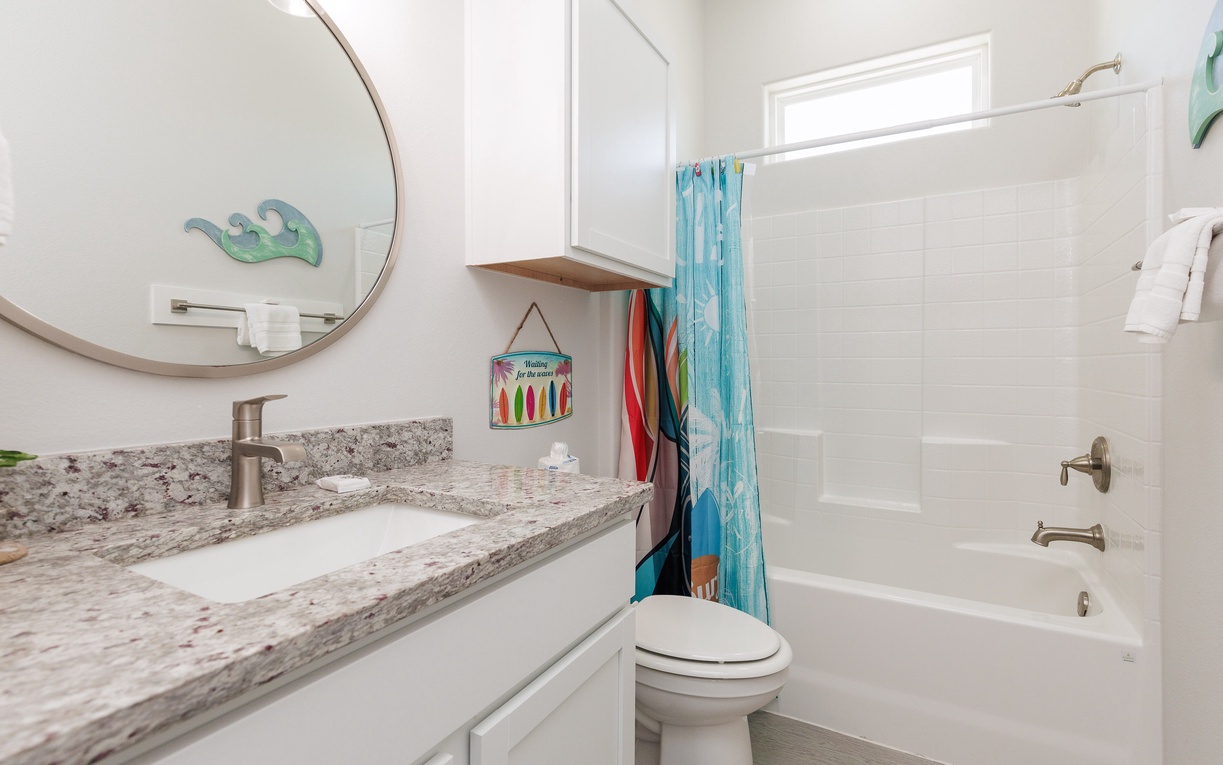 Refresh in this bright, modern bathroom with a luxurious granite vanity, spacious tub-shower combo, and cheerful coastal touches.