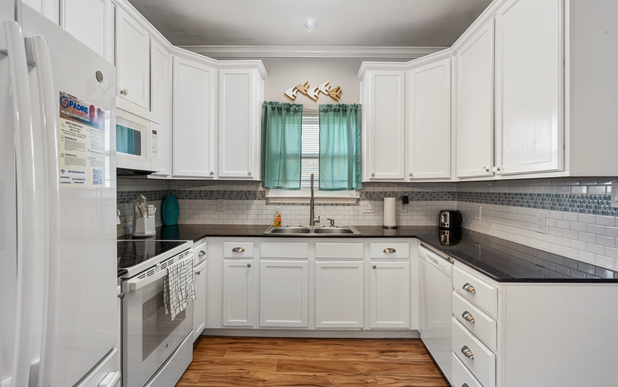 Step into your bright, fully equipped kitchen where coastal charm meets practical comfort. With crisp white cabinetry, sleek appliances, and warm wood floors, this inviting space makes preparing meals feel effortless and enjoyable.