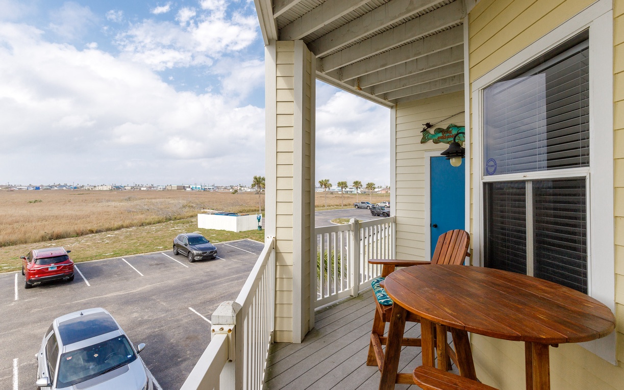 Relax at your private wooden table on this covered balcony, overlooking peaceful coastal views and convenient parking below.