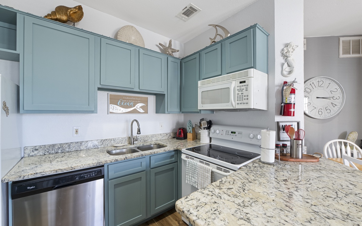 Your coastal-themed kitchen awaits with sea-green cabinets, granite counters, and full appliances for preparing memorable vacation meals.