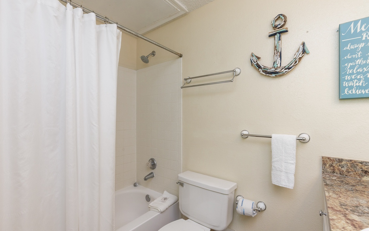 Fresh towels await your arrival in this clean, coastal-themed bathroom complete with tub-shower combo for your comfort.