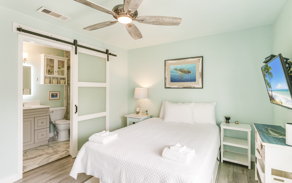 Wake up refreshed in your serene coastal bedroom, where soothing aqua walls and crisp white linens create a peaceful retreat. The barn-door bathroom and gentle ceiling fan complete your beach-inspired escape.