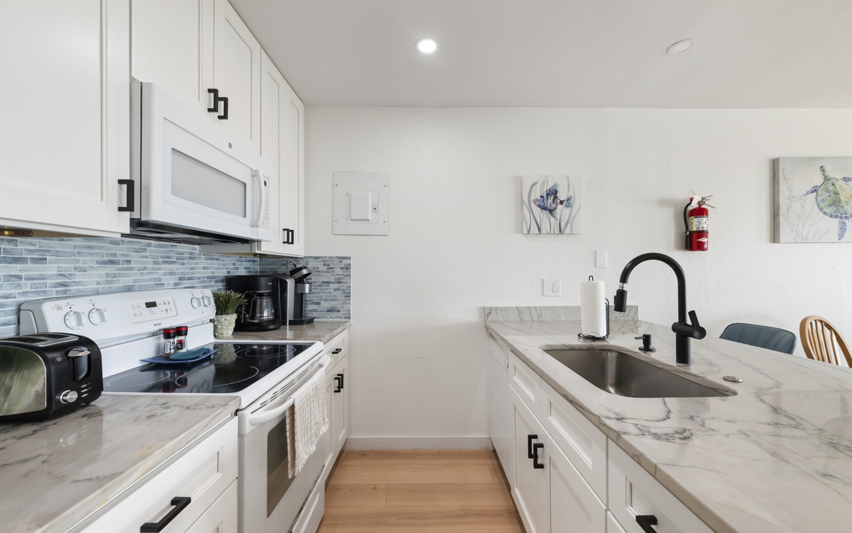 Your bright, fully-equipped kitchen invites easy meal prep with modern appliances, marble countertops, and coastal-inspired backsplash—perfect for morning coffee or home-cooked dinners.