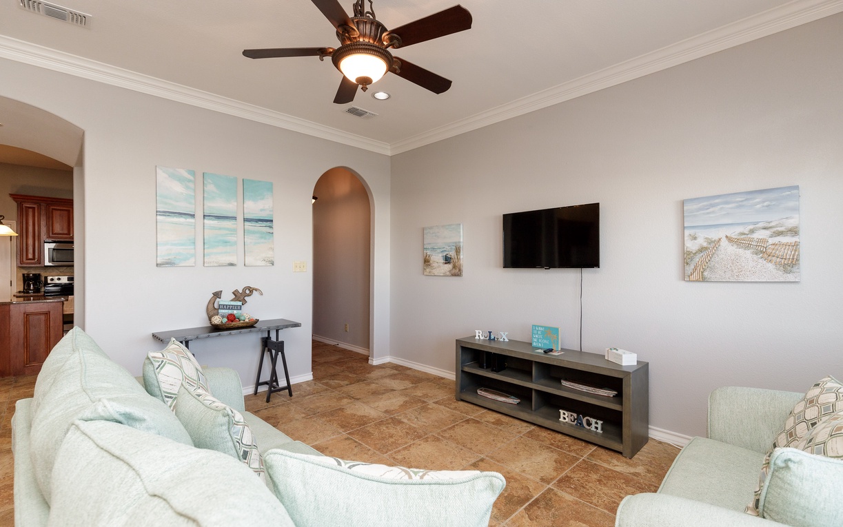 Relax in your bright, airy living room with coastal artwork and comfortable seating, perfect for unwinding after beach adventures.