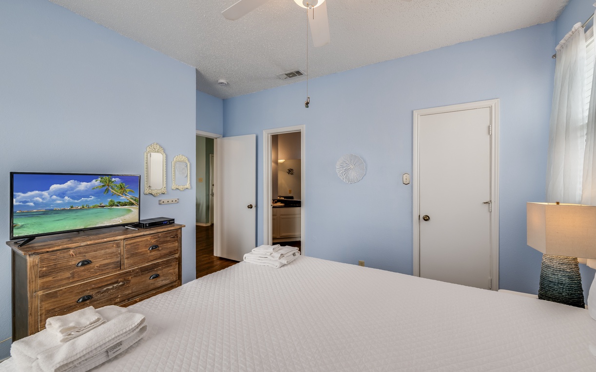 Another view of the primary bedroom showcasing a dresser with TV, ample storage, and an inviting layout designed for a restful stay.