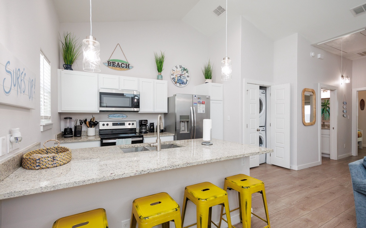 Your bright kitchen features granite counters, stainless appliances, and cheerful yellow bar stools perfect for morning coffee or casual meals together.