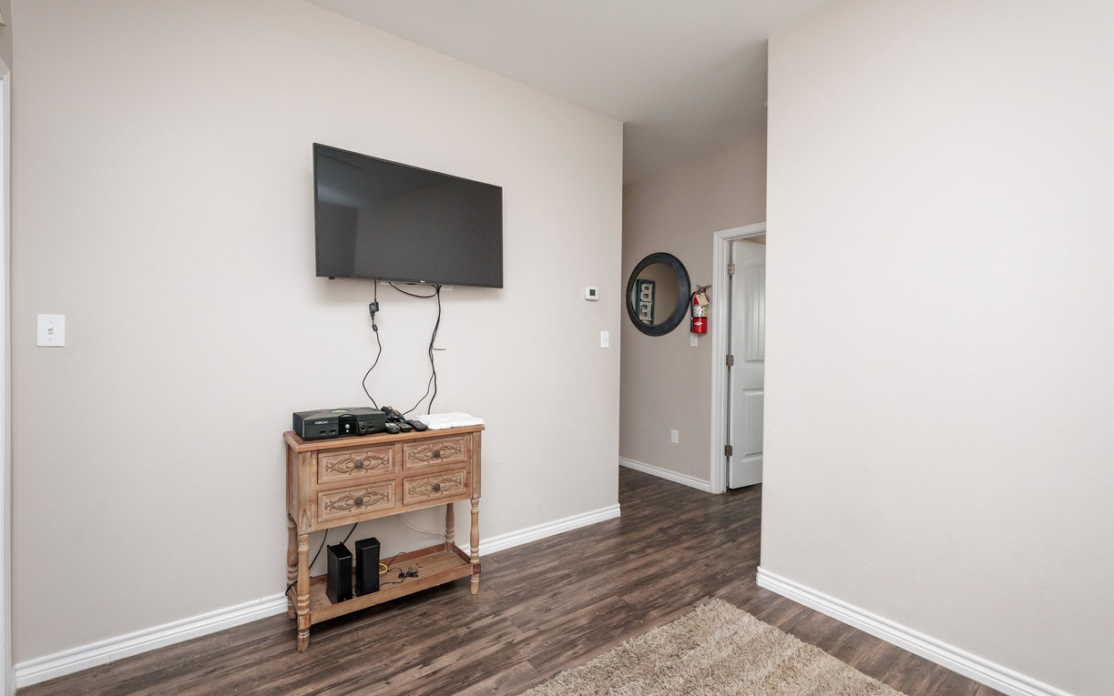 Unwind in your cozy entertainment space with a large flat-screen TV and charming wooden console for all your relaxation needs.