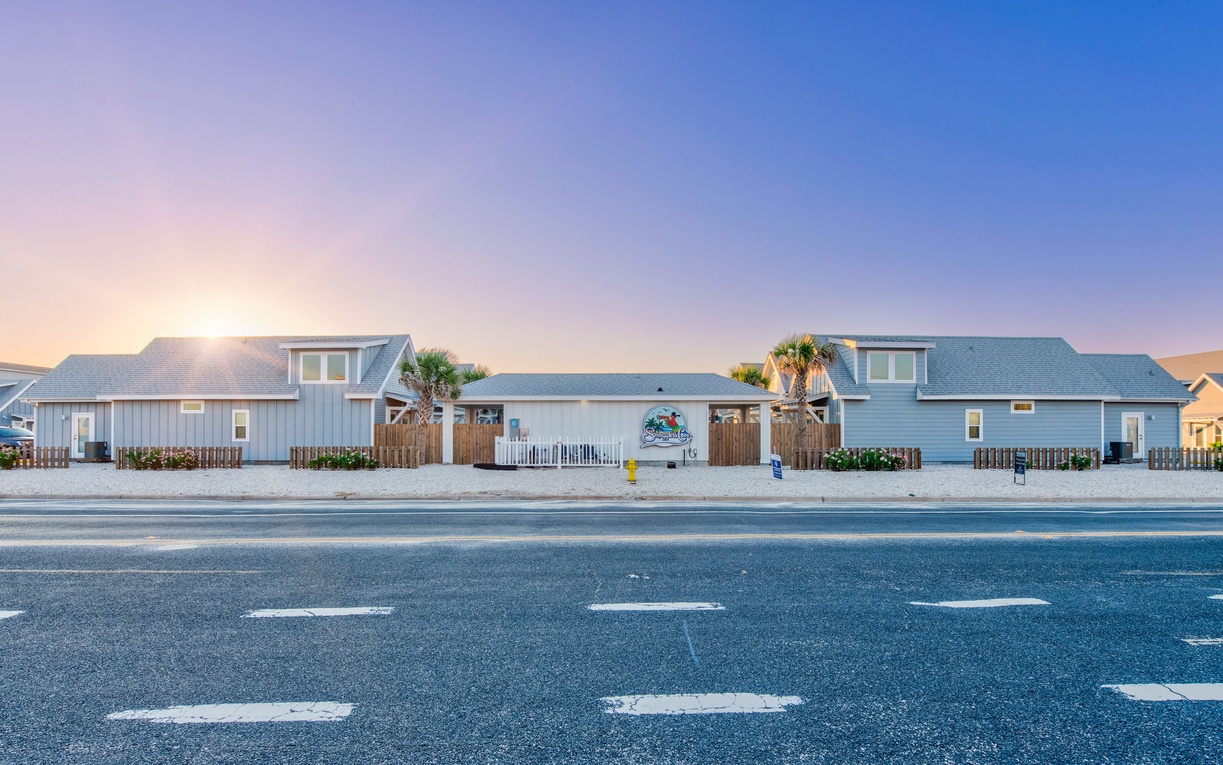 Coastal rental property featuring multiple blue units with palm trees and convenient street access for easy arrival.