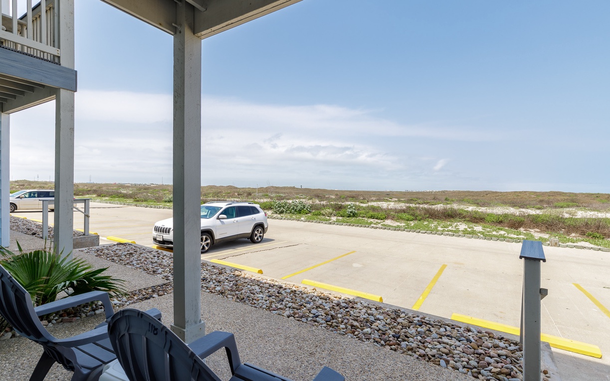 A covered parking area provides convenient vehicle access with natural landscape views beyond the property grounds.