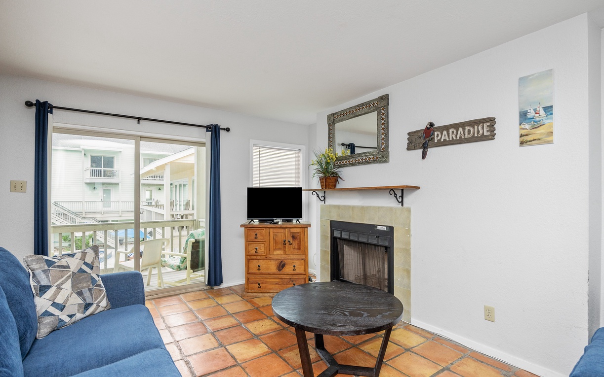 Settle into this cozy living room with fireplace, TV, and charming coastal decor—your perfect retreat after beach adventures.