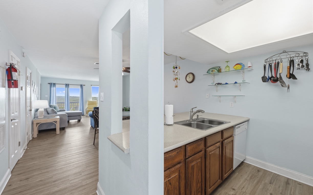 Your open-concept space flows effortlessly from kitchen to living room, with warm wood cabinetry, practical counter space, and bright natural light welcoming you home.