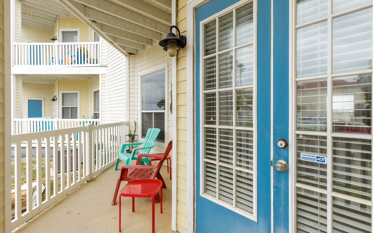 Step onto your private balcony featuring colorful outdoor chairs where you can relax and enjoy the coastal atmosphere.