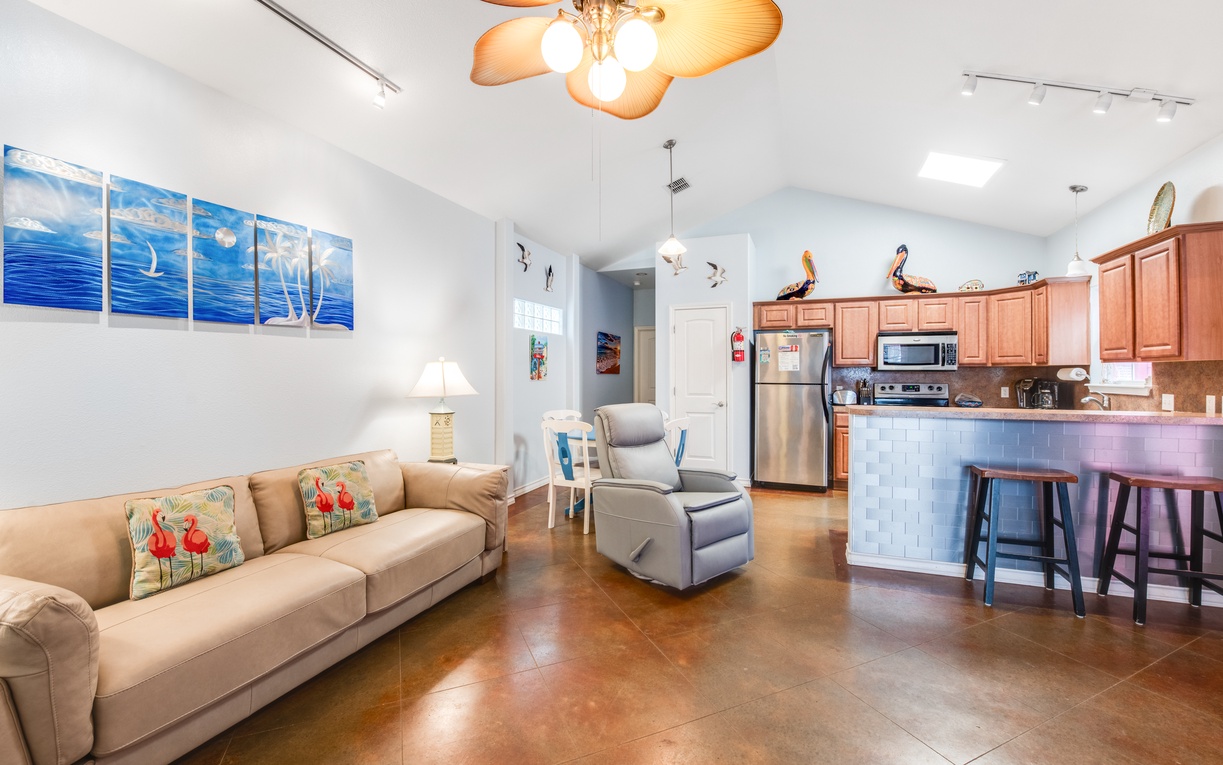 Settle into this bright open living space where coastal artwork and comfortable seating create your perfect home base for relaxation.
