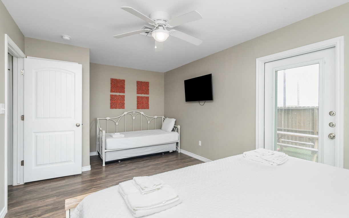 Relax in your comfortable bedroom with a daybed for extra guests, ceiling fan, and mounted TV for cozy evenings.
