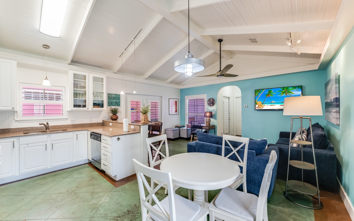 Your coastal retreat features open-plan living with turquoise walls, white kitchen, and tropical touches creating the perfect beach house atmosphere.