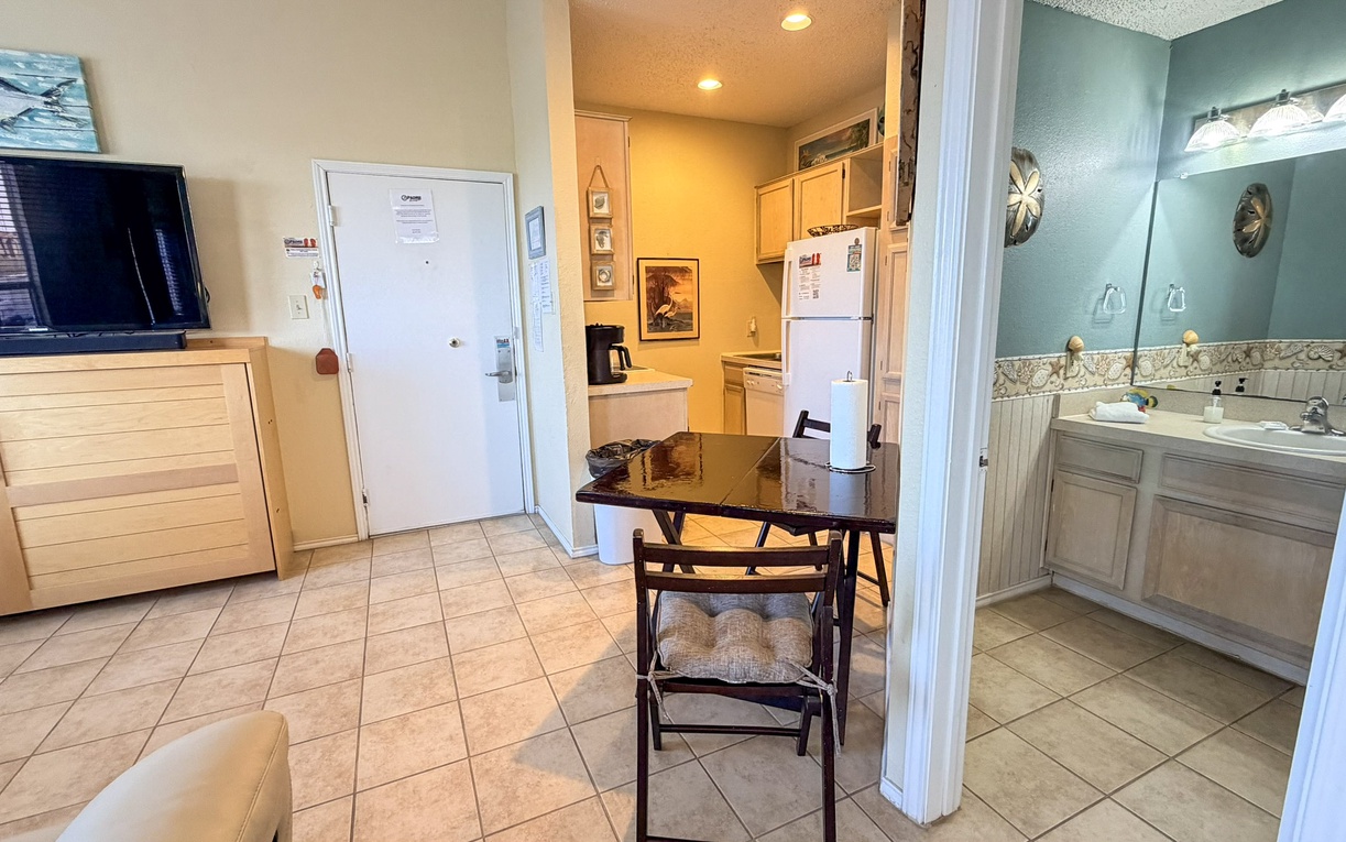 Your cozy coastal retreat features an open layout with kitchen, dining space, and glimpse of the bathroom—perfect for unwinding.