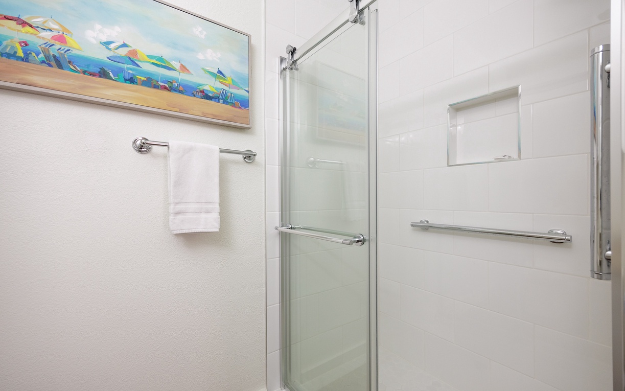 Step into your pristine bathroom featuring a spacious walk-in shower with safety rails and fresh towels ready for your comfort.