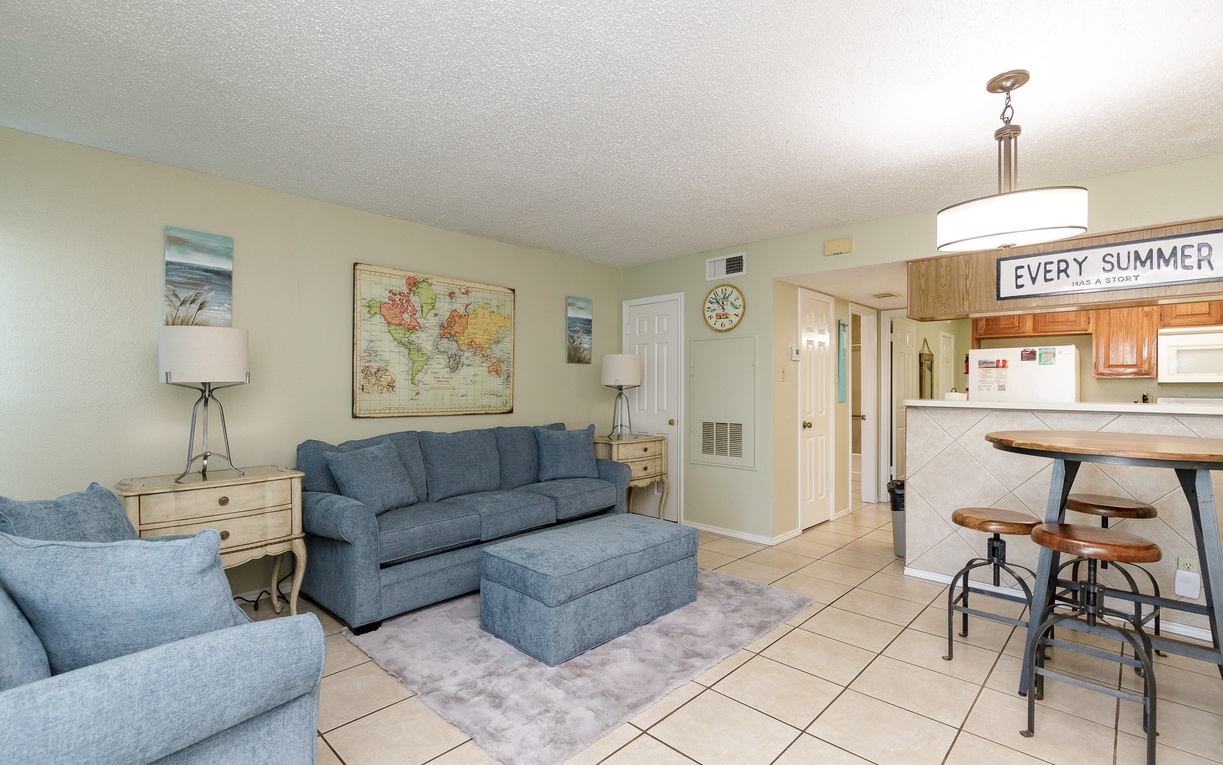 Relax in your bright, beachy living space featuring comfy blue sofas and a fully equipped kitchen for memorable vacation meals together.
