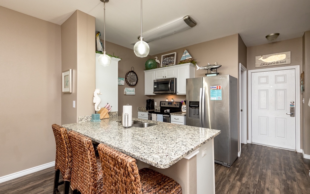 Your spacious kitchen features granite counters, full appliances, and coastal-themed decor that sets the perfect stage for vacation meal prep.