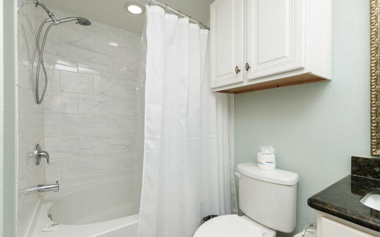 Step into your pristine bathroom featuring a luxurious tub-shower combo with marble-style tiles and crisp white curtain for relaxing baths.