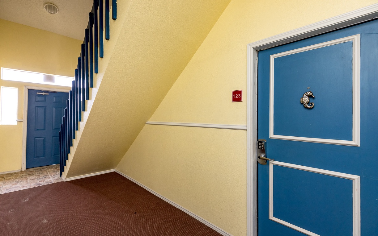 Your comfortable stay awaits behind these cheerful blue doors in this well-maintained hallway with easy stair access.