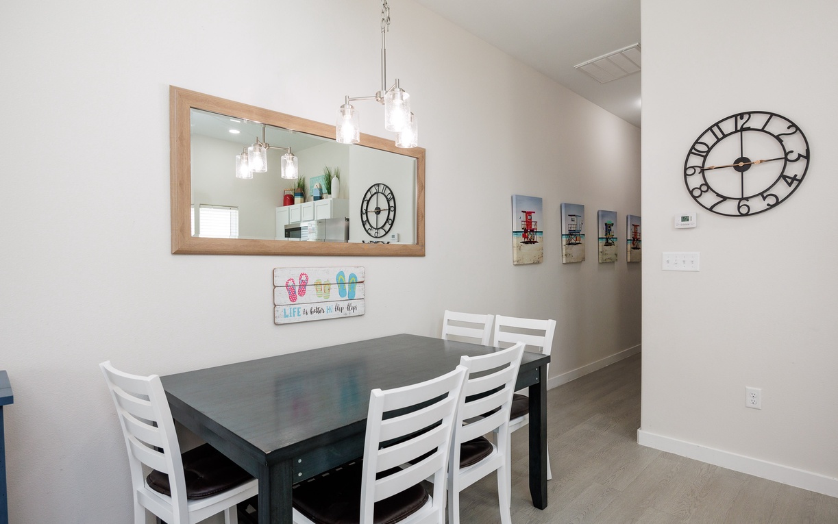 Gather around your spacious dining table for memorable meals, with elegant pendant lighting and charming coastal decor creating the perfect atmosphere.