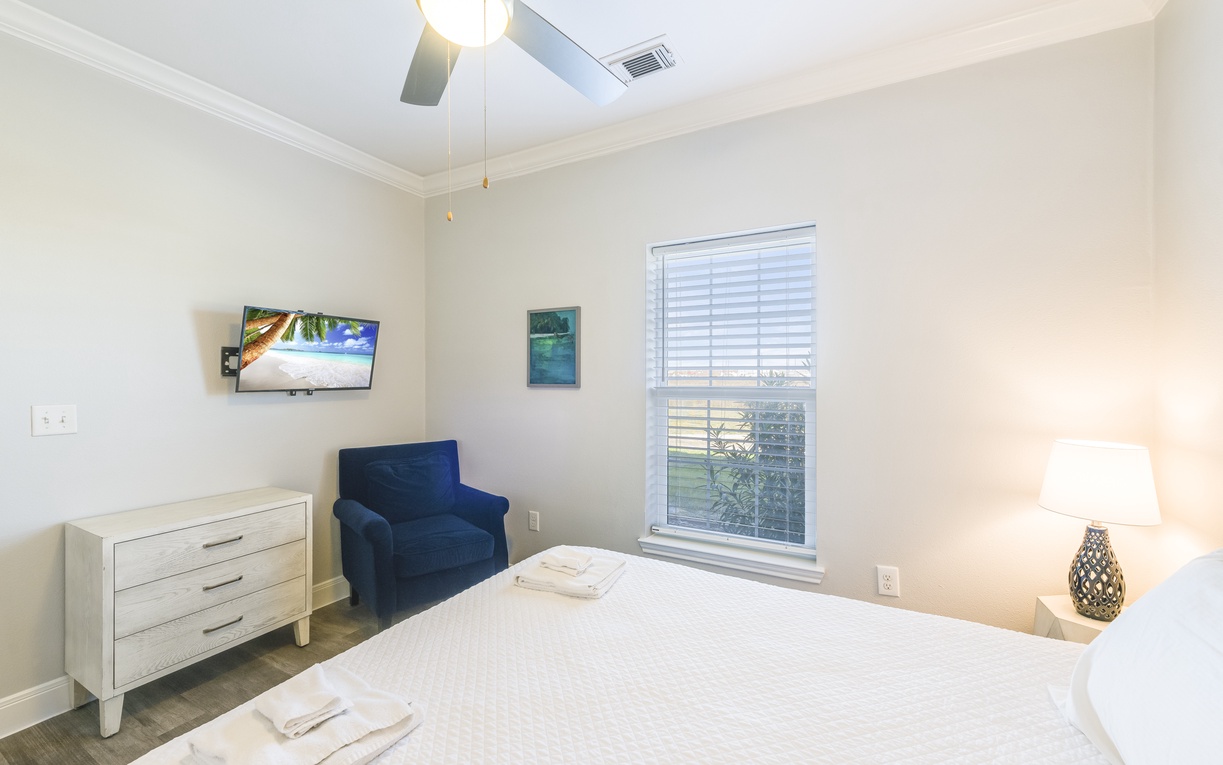 Relax in your bright, comfortable bedroom with premium linens, wall-mounted TV, and cozy reading chair for the perfect getaway retreat.