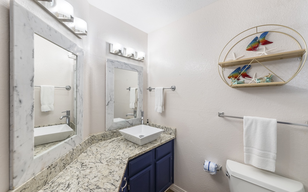 Refresh in your beautifully appointed bathroom featuring granite countertops, vessel sink, and charming coastal decor touches.