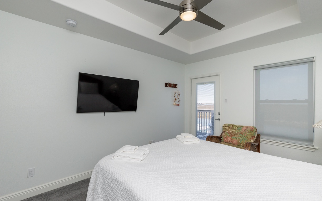 Unwind in your peaceful bedroom with crisp linens, modern ceiling fan, and wall-mounted TV for cozy evenings after exploring the area.