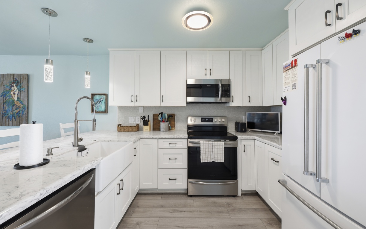Your fully equipped kitchen features modern stainless appliances, gleaming marble countertops, and crisp white cabinetry—everything you need to prepare delicious home-cooked meals during your stay.