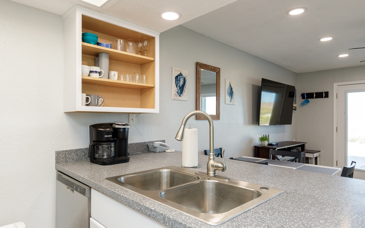 Your fully equipped kitchen awaits with granite counters, coffee maker, and open shelving stocked with essentials for your perfect getaway.