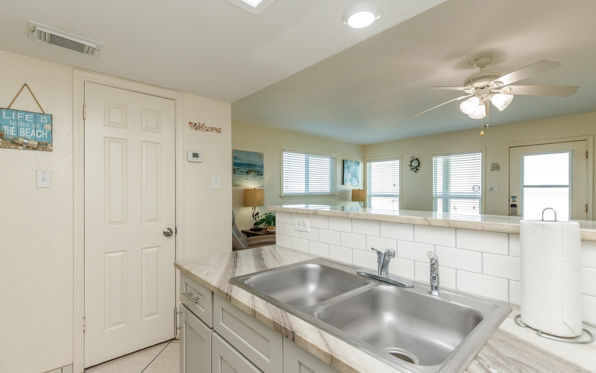 Your bright kitchen features marble countertops and a double sink, perfect for preparing meals with ocean-inspired decor surrounding you.