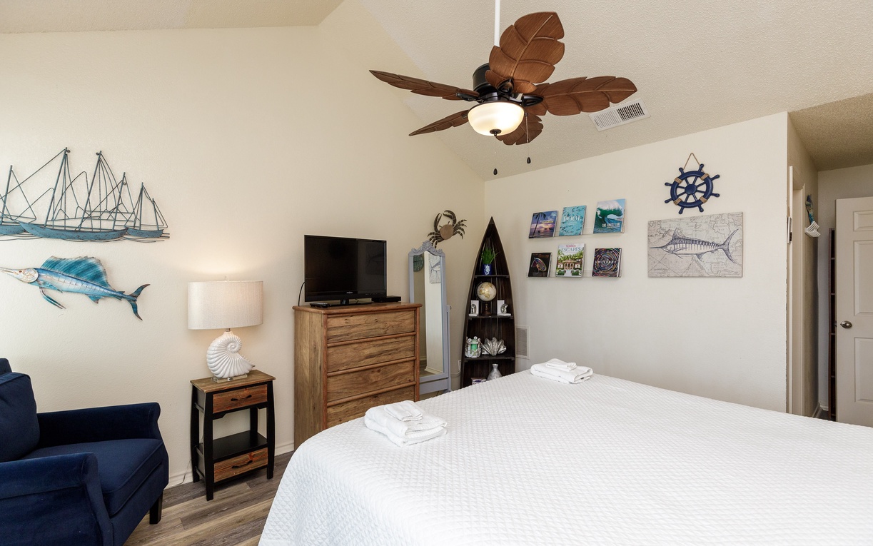 Drift into coastal dreams beneath your tropical ceiling fan in this nautical-themed bedroom, where maritime artwork and crisp linens create your perfect seaside retreat.