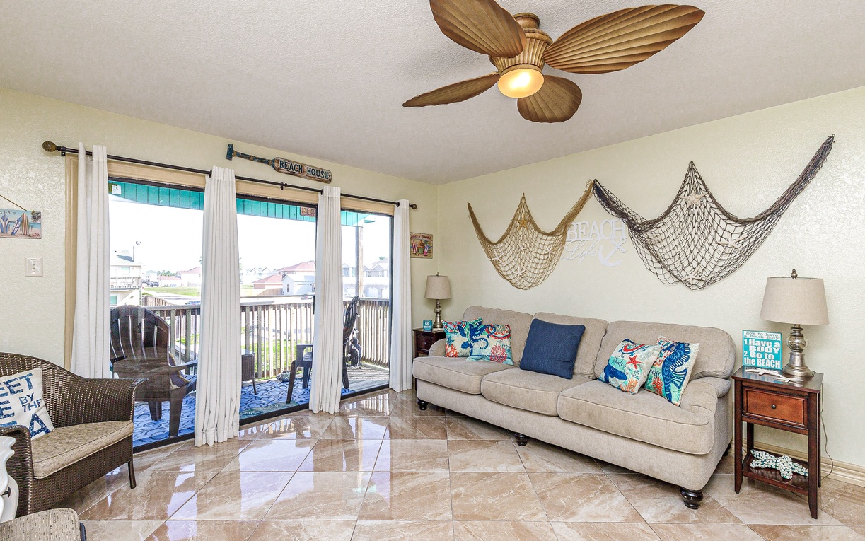 Your coastal-themed living room welcomes you with nautical charm and bright balcony views for perfect beach vacation relaxation.