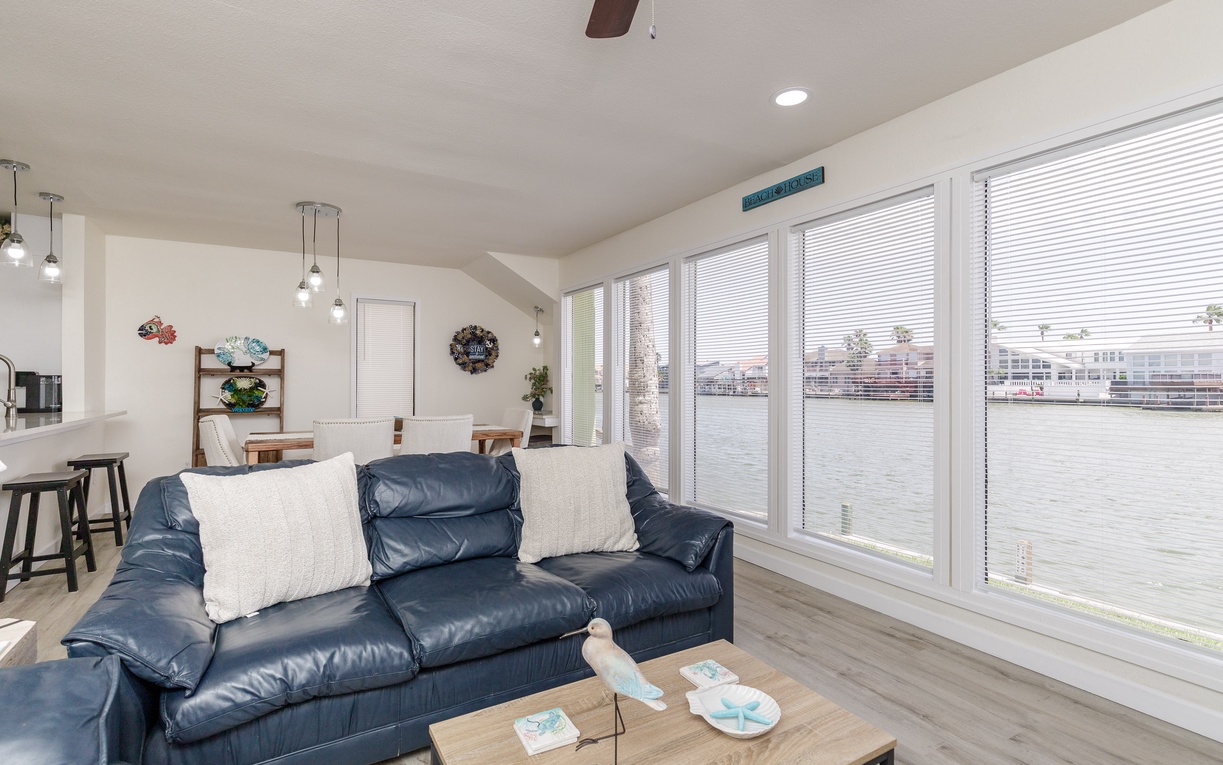 Relax on plush leather seating while panoramic windows frame stunning waterfront views in your bright, modern living space.