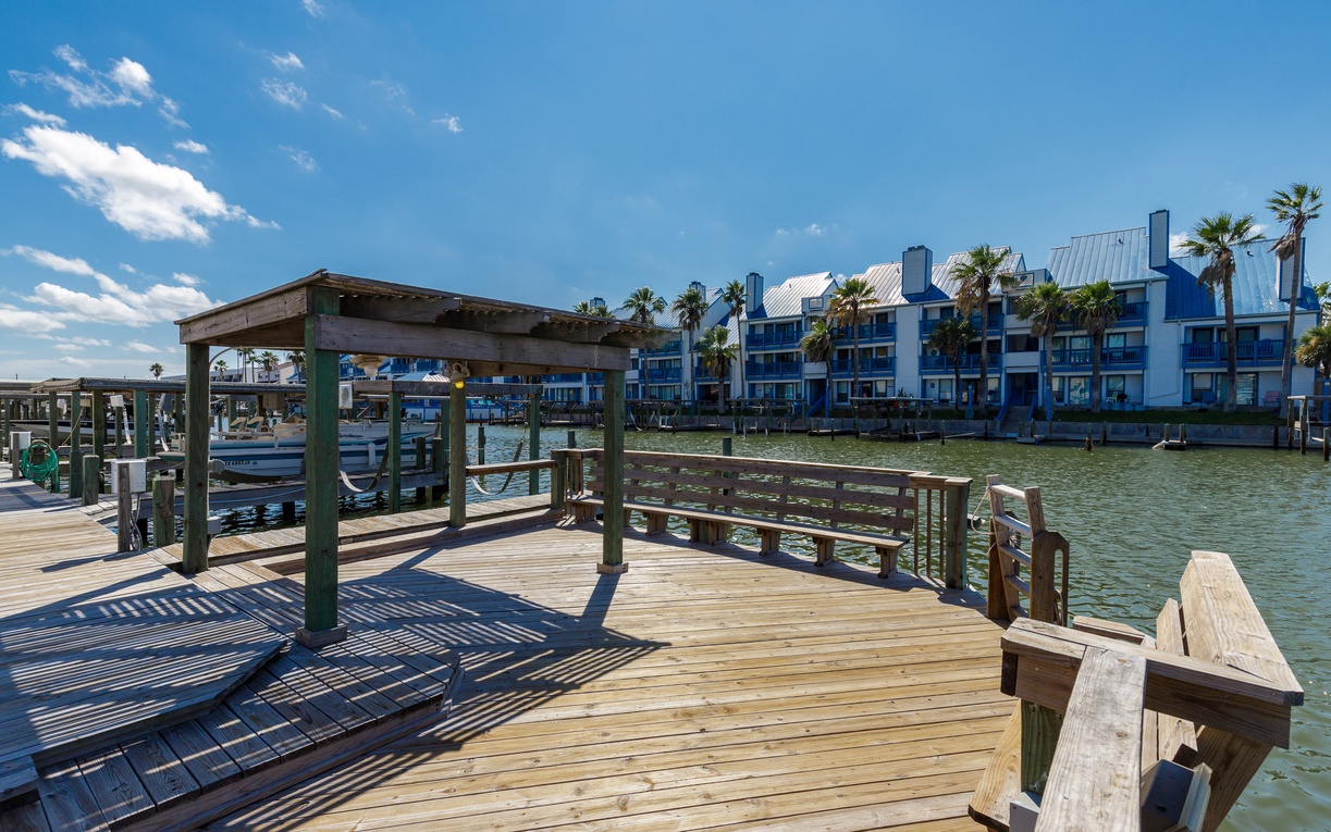 Waterfront property with private dock and boats overlooking calm bay waters under blue skies.