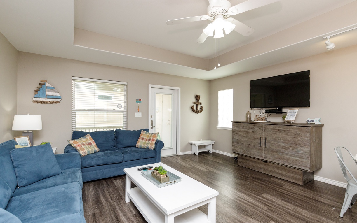 Unwind in your spacious living room with plush blue seating, nautical touches, and entertainment center—perfect for relaxing after beach days.