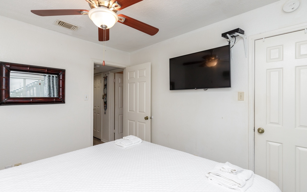 Unwind in your peaceful bedroom with a comfortable bed, ceiling fan for cooling, and wall-mounted TV for entertainment.