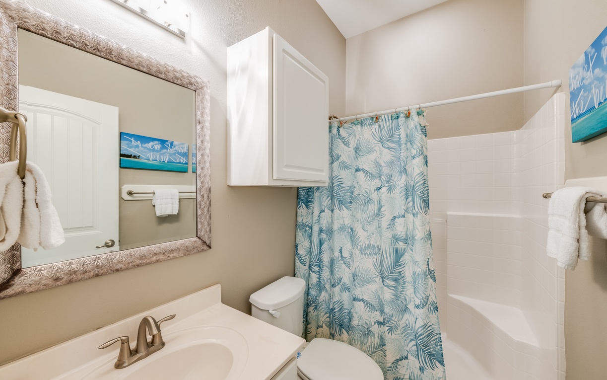 Step into your coastal-inspired bathroom featuring tropical touches and fresh white linens for your comfort.
