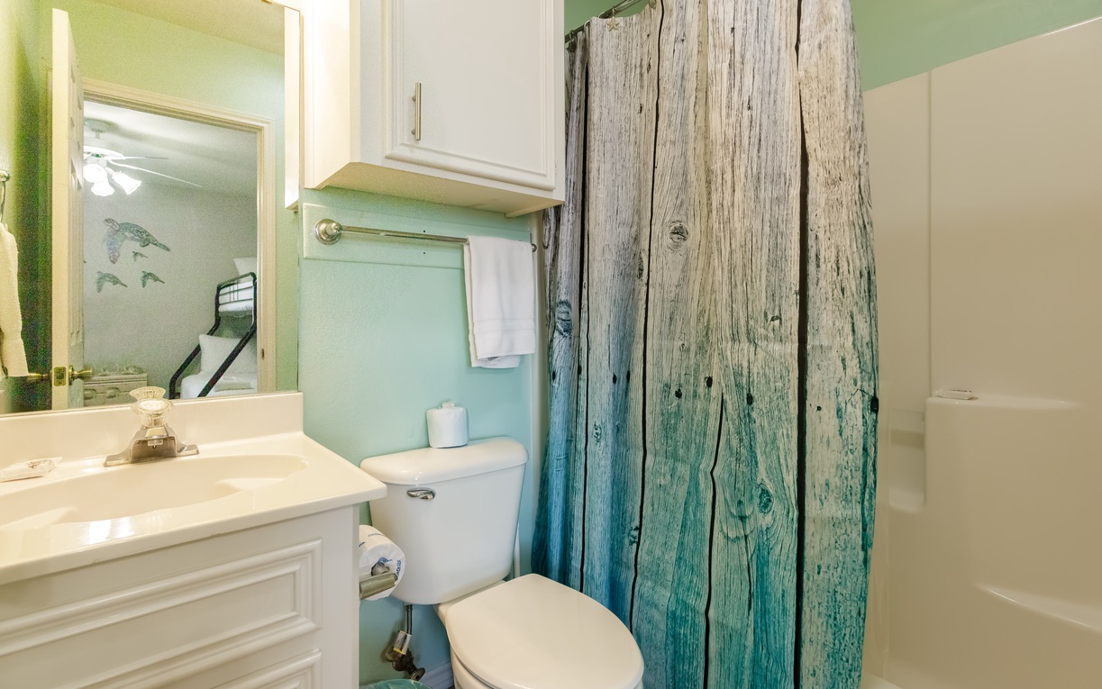 Your coastal-themed bathroom features rustic driftwood accents and soothing sea-glass colors, creating a beachy retreat.