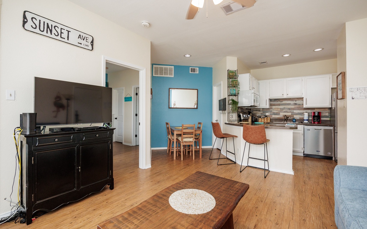 Unwind in your bright open-plan space where coastal vibes meet modern comfort, featuring a fully equipped kitchen and cozy seating.